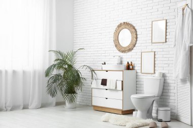 Seramik klozeti, lavabosu ve şifoniyeri olan şık bir banyo.