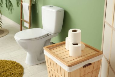 Seramik klozet, kağıt rulo ve sepetli şık tuvaletler.