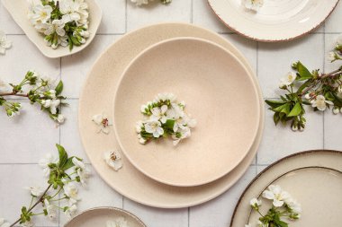 Beyaz fayans zemininde çiçek açan dalları olan temiz bej plakalar.