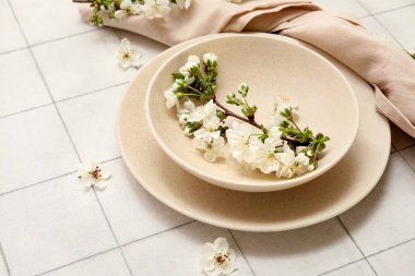 Beyaz seramik zemin üzerinde çiçek açan dallı bej plakalar, yakın plan