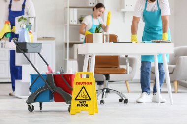 Ofisi temizleyen temizlikçilere karşı malzemelerle dolu bir araba.