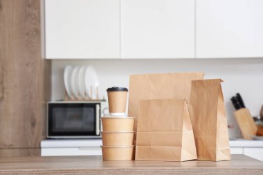 Mutfaktaki sehpanın üzerinde kahve fincanı olan kağıt poşetler. Yemek dağıtım servisi.