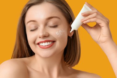 50 numara güneş kreminden yapılmış güzel bir kadın ve sarı arka planda bir tüp.