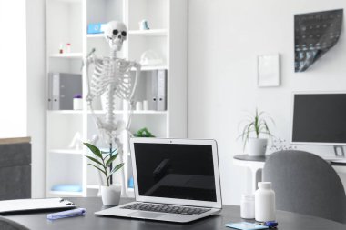 İnsan iskeleti modeli, röntgen görüntüleri, modern dizüstü bilgisayar ve ışık hastanesi.