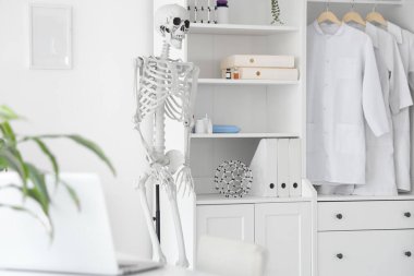 Masada insan iskeleti modeli ve modern dizüstü bilgisayarı olan hafif bir hastane.