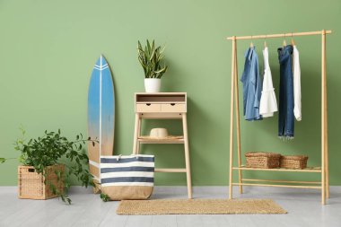 Elbise askısı, masa, ev bitkileri ve sörf tahtasıyla şık bir oda.