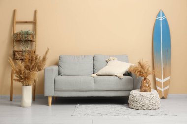 Gri kanepesi, otları ve sörf tahtası olan şık bir oturma odası.