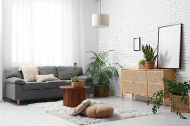 Gri kanepesi, ahşap dolabı, sehpası ve sepetleri olan şık bir oturma odası.