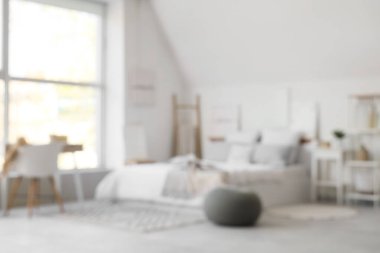 Konforlu yatak odası, puf ve pencere kenarındaki çalışma alanı bulanık görünüyor.