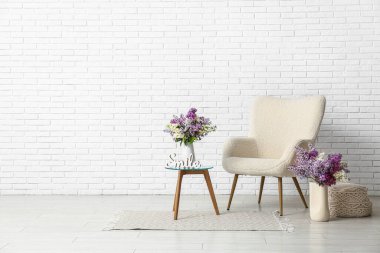 Oturma odasının içinde vazolarda koltuk, masa ve leylak çiçekleri var.