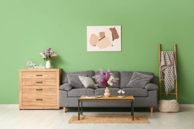 Kanepe, masa ve vazolarda leylak çiçekleri olan oturma odasının içinde.