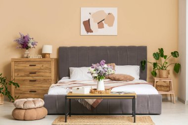 Yatak odasının içinde vazolarda leylak çiçekleri var.