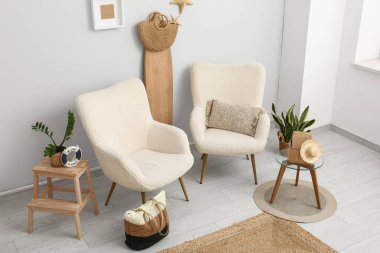 Beyaz koltuklu, el çantalı, sörf tahtalı ve yaz dekorlu şık bir oturma odası.