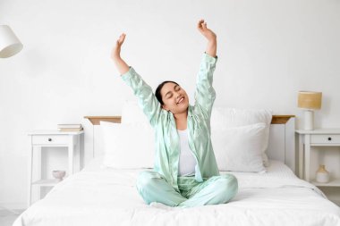 Gülümseyen genç kadın yatak odasında geriniyor.