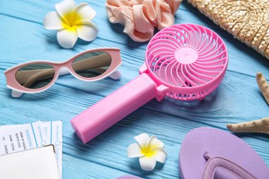 Kadın yaz aksesuarları ve mavi ahşap arka planda mini fan.