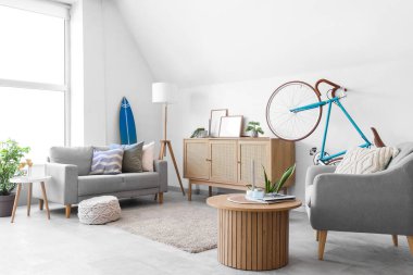 Bisiklet, kanepe ve koltuklu aydınlık oturma odasının içinde.