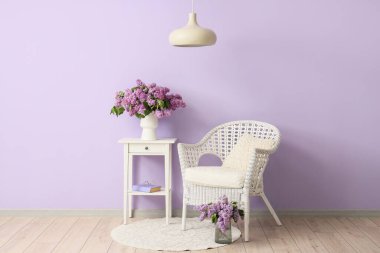 Oturma odasının içinde vazolarda koltuk, masa ve leylak çiçekleri var.