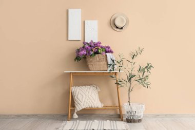 Odanın içinde masa ve çantanın içinde leylak çiçekleri var.