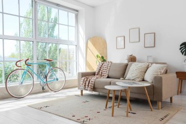 Oturma odasının içinde bisiklet, kanepe ve masalar var.