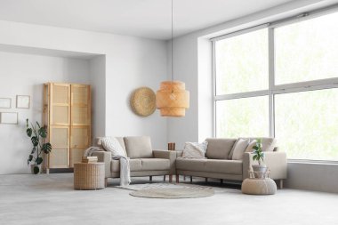 Oturma odasının içinde kanepeler ve büyük pencereler var.