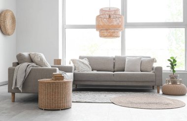 Oturma odasının içinde kanepeler ve büyük pencereler var.