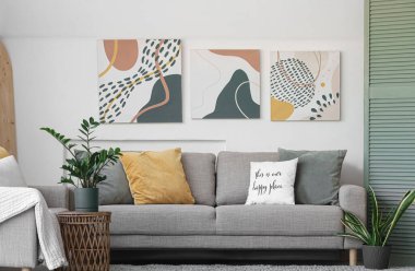 Oturma odasının içinde kanepe ve çiçek var.