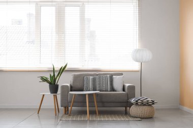 Oturma odasının içinde kanepe, masa, lamba ve çiçek var.