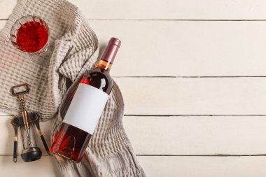 Beyaz ahşap zemin üzerinde boş etiketli, cam, açacağı ve mantarlı bir şişe şarap.