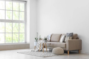 Gri kanepe, masa ve puf ile aydınlık oturma odasının içi