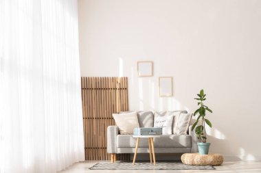 Gri kanepeli, masalı ve katlanmış ekranlı aydınlık oturma odasının içi.