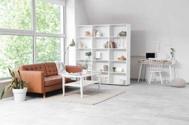 Raf ünitesi, kanepesi ve işyeri olan aydınlık oturma odasının içinde.