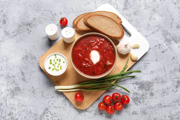 Bir kase lezzetli Ukrayna çorbası, ekşi krema ve gri arka planda malzemeler.