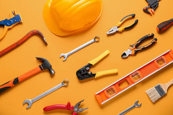 Hardhat и строительные инструменты на оранжевом фоне