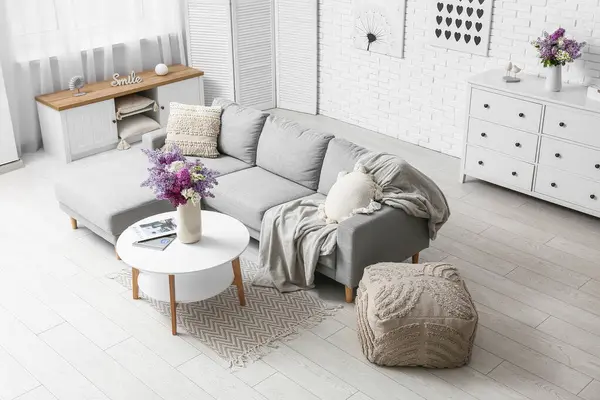 Kanepe, masa ve vazolarda leylak çiçekleri olan oturma odasının içinde.