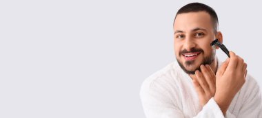 Bornozlu genç adam beyaz arka planda tıraş olurken mesaj için yer açıyor.