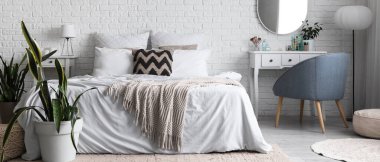 Yatak odasının içinde yatak odası, ayna ve kozmetik ürünler beyaz tuğlaların yanında makyaj masasında.