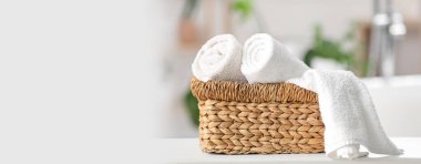 Tuvaletteki masanın üzerinde temiz havlular olan hasır sepet. Tasarım için pankart