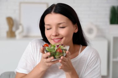 Evde bir kase taze sebze salatasıyla güzel bir genç bayan. Kilo verme konsepti
