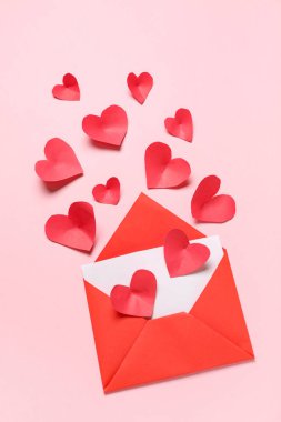 Zarflı kompozisyon, kart ve pembe arka planda kırmızı kağıt kalpler. Sevgililer Günü kutlaması