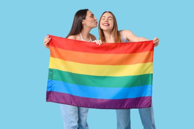 Mavi arka planda LGBT bayrağı olan güzel bir lezbiyen çift.