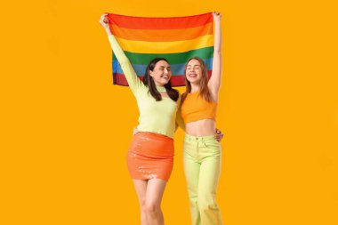 Sarı arka planda LGBT bayrağı olan güzel bir lezbiyen çift.