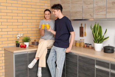 Mutlu genç çift mutfakta taze meyve suyu içiyor.