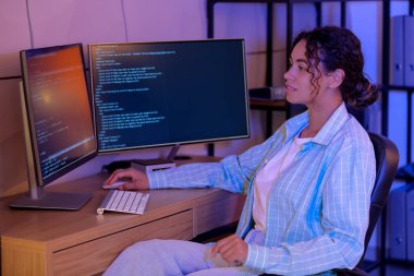 Genç Afro-Amerikalı soru cevap mühendisi geceleri bilgisayarla çalışıyor.