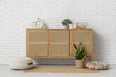 Çekmeceler, saksılar ve beyaz tuğla duvarın yanındaki puflar.