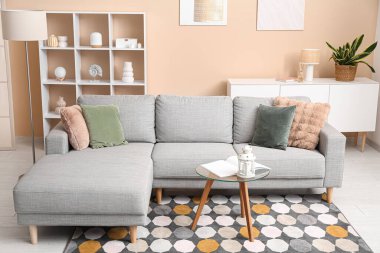 Konforlu kanepe, içinde fener ve kitap olan kahve masası oturma odasının içinde.