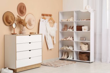 Kadın ayakkabıları, aksesuarları ve kıyafetleriyle modern soyunma odasının şık bir iç mekanı.