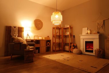 Geceleri şömineli, koltuklu ve parlayan lambalı oturma odasının içinde.