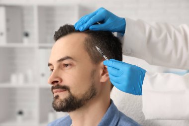 Klinikte saç büyütme iğnesi yaptıran yakışıklı adam, yakın plan.