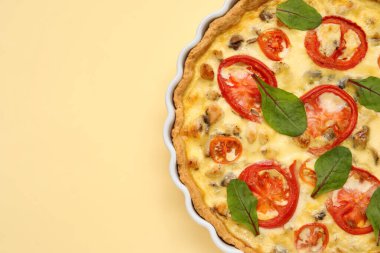 Sarı arka planda ıspanak yapraklı lezzetli domates tartı.