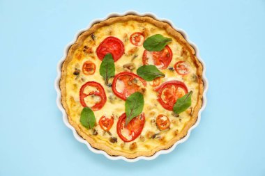 Mavi arka planda ıspanak yapraklı lezzetli domates tartı.